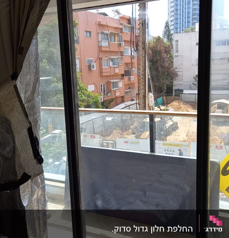 חלון זכוכית גדול עם וילון בצד